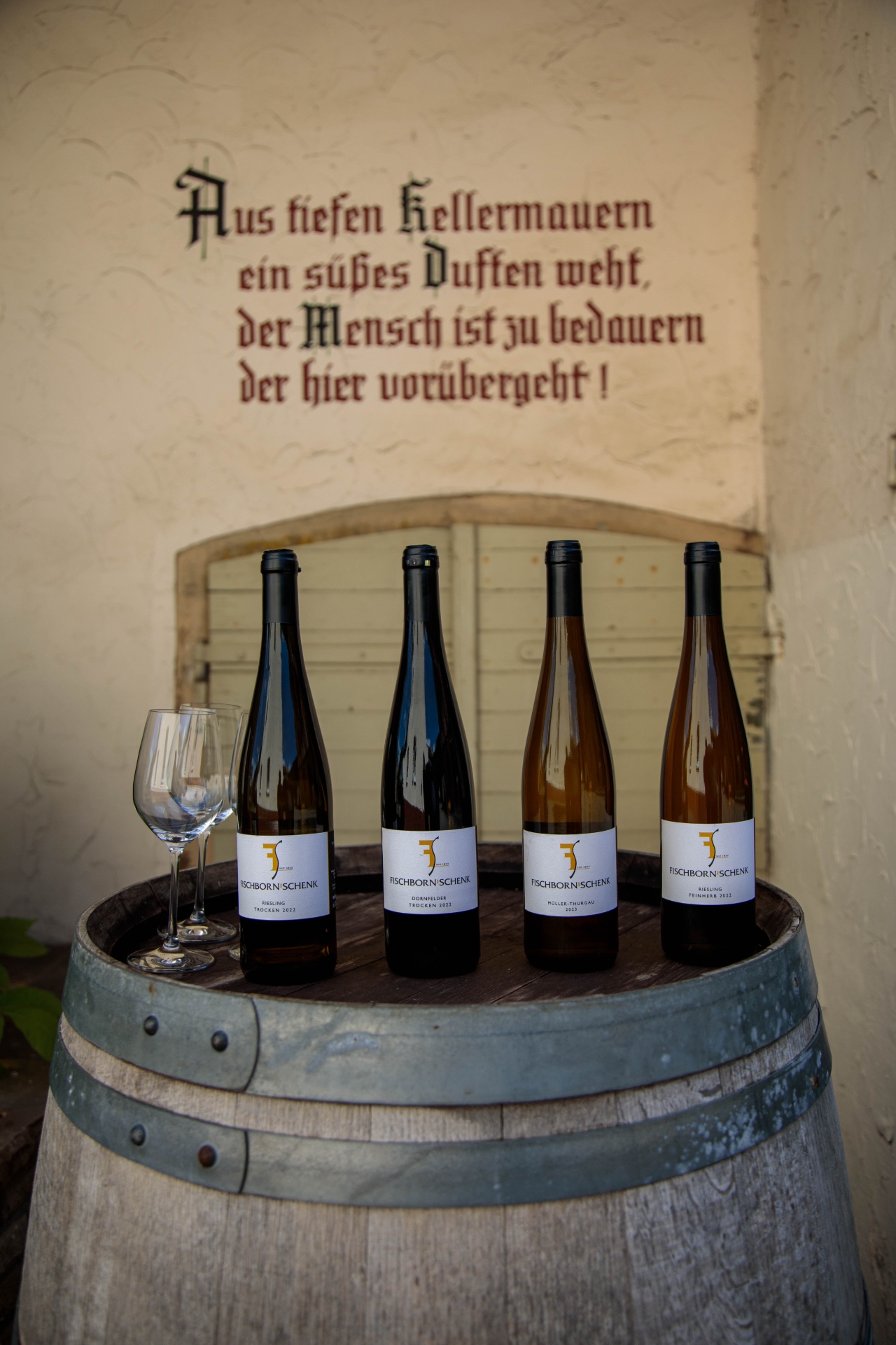 Fischborn-Schenk Müller-Thurgau bottles on a wine barrel beside hydrangeas
